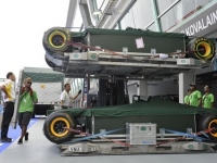 Logistics staff move in a team lotus car into the garage